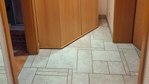 A room with a wooden wardrobe, tiled floor, and a door leading to another room. - Vacation apartment Am Ranis (Oederan)