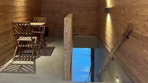 Un interior de madera con comedor, una escalera y vista por una ventana.