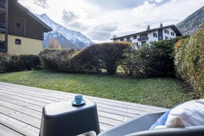 Een terras met een blauw kopje op een schoteltje, omgeven door groen en een berg op de achtergrond.