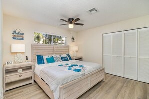 A bedroom with a bed, nightstands, a ceiling fan, a window with a view, and a closet. - The Rockledge Billiard House (Rockledge)
