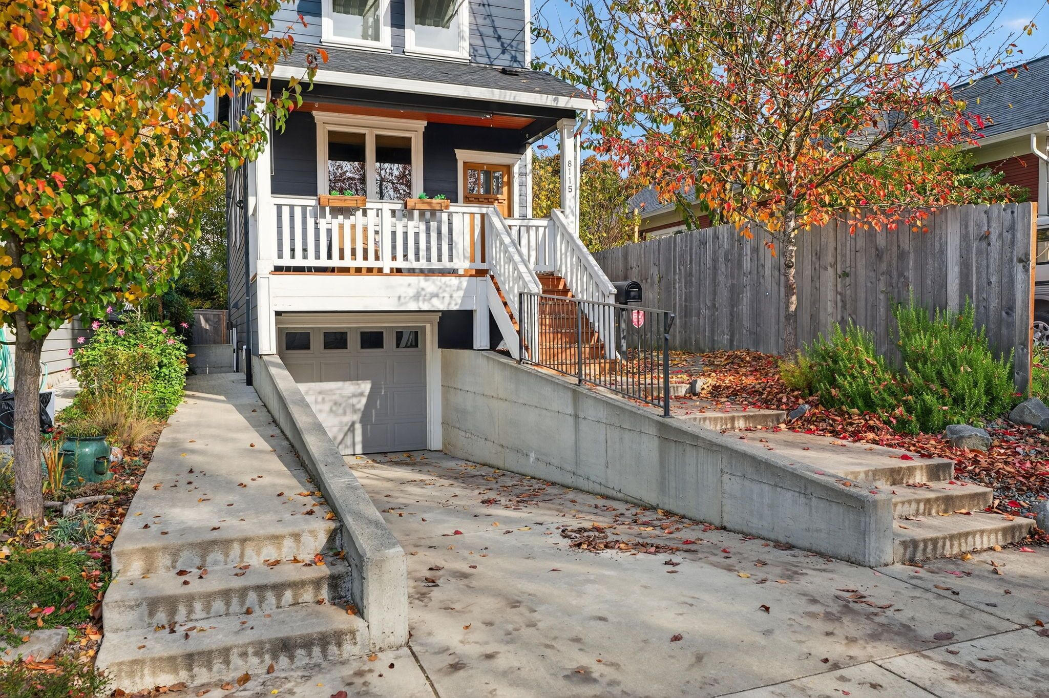 Ein zweistöckiges Haus mit Veranda, Garage und Holzzaun.