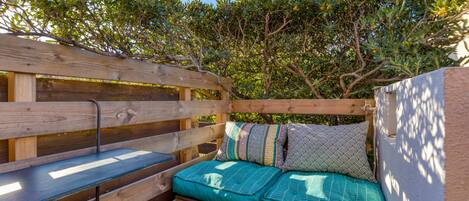 Un banc en bois avec un coussin, une table en bois et une vue sur les arbres.