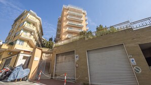 Un edificio residencial de varios pisos con balcones, una entrada con portón y un cerramiento para el garaje.