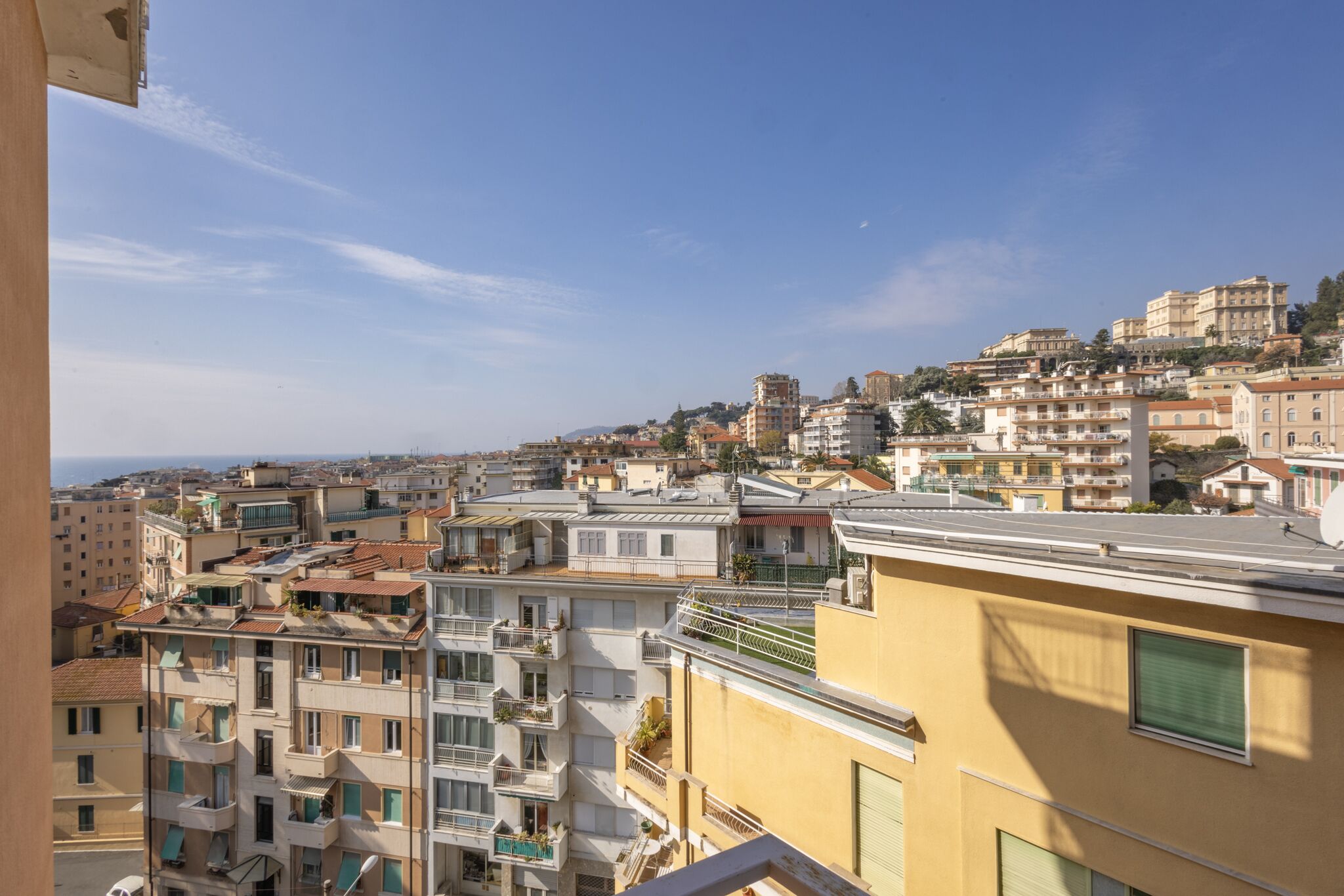 A cityscape with multi-story buildings, balconies, and a clear sky.
