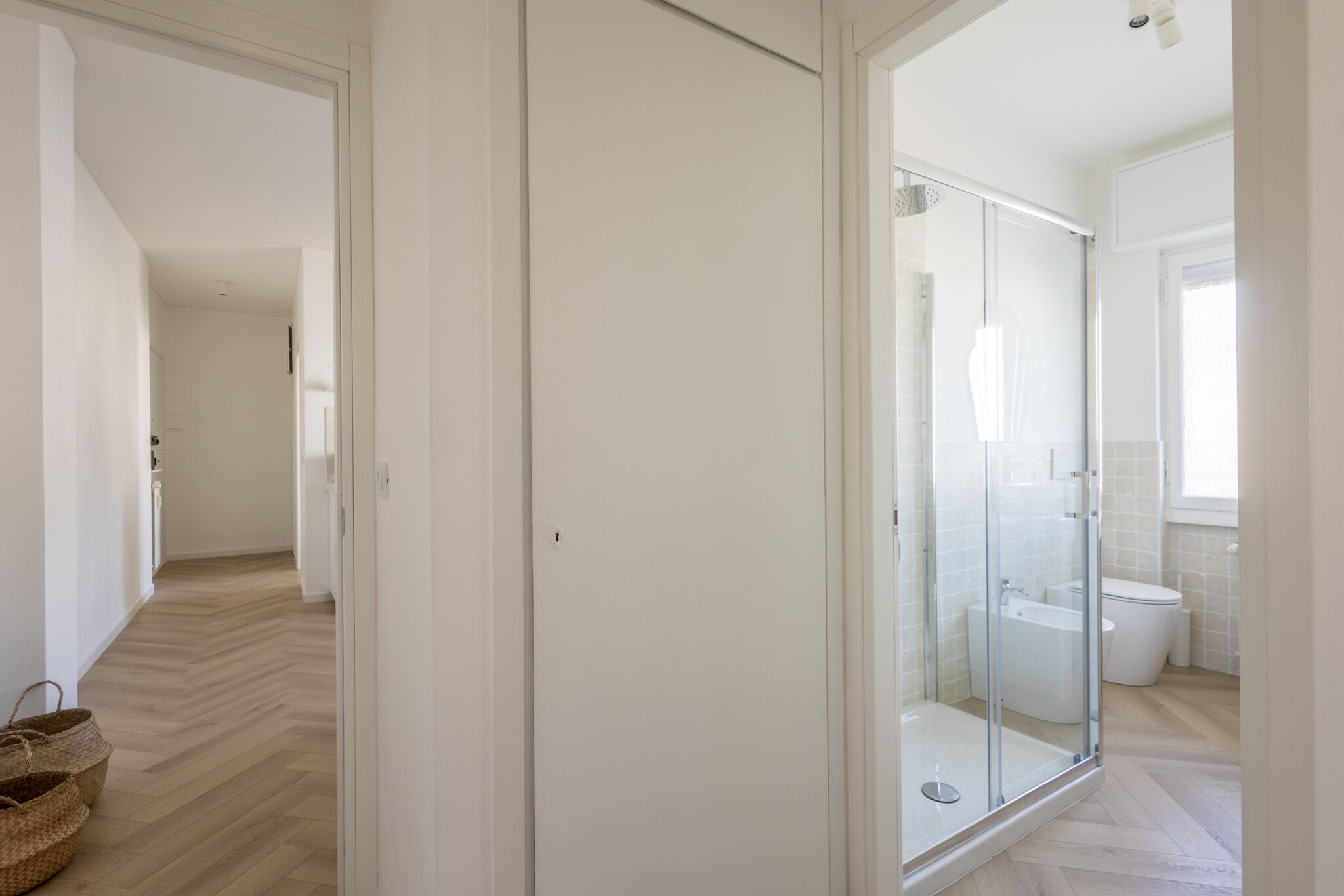 A modern bathroom with a glass shower enclosure, a toilet, and a bidet.