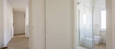 A modern bathroom with a glass shower enclosure, a toilet, and a bidet.