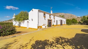 Un bâtiment blanc avec une base jaune, un clocher et une colline en arrière-plan.