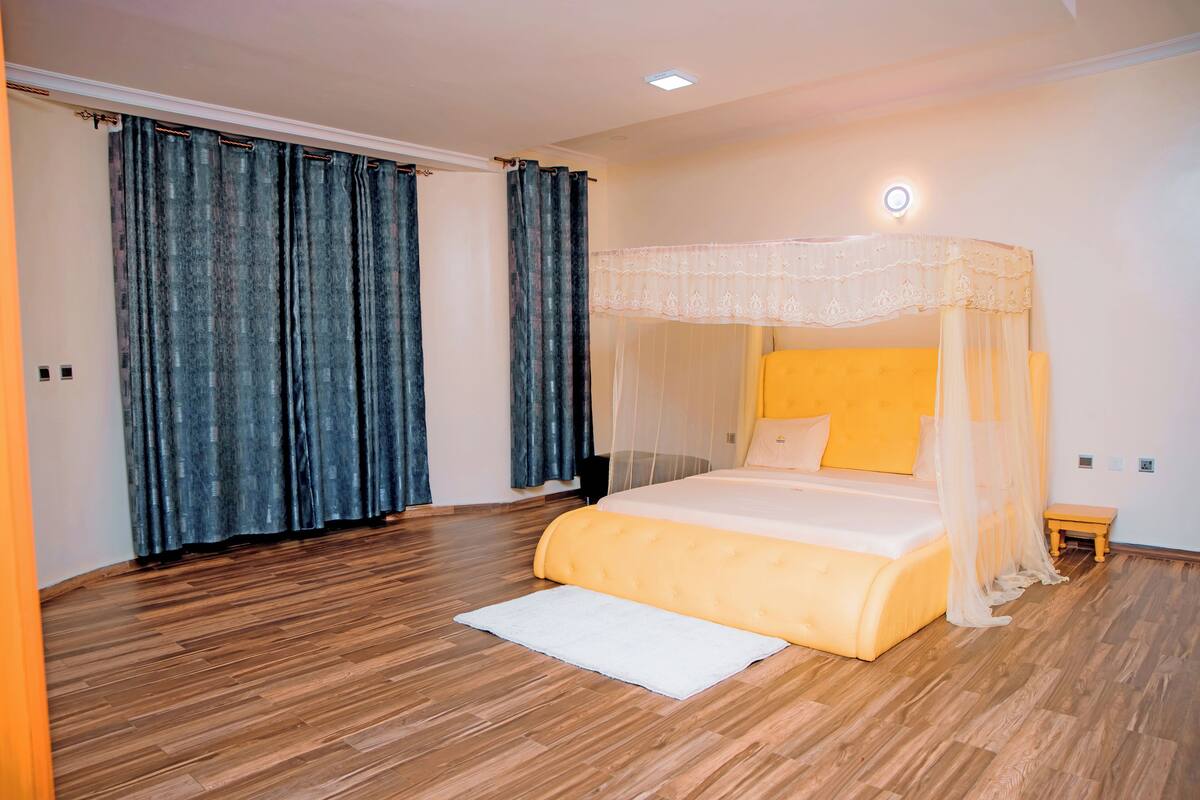 A bedroom with a bed, curtains, a bedside table, and a nightstand.