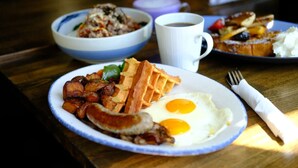 A breakfast plate with eggs, bacon, and waffles on a wooden table. - THE MOON APARTMENTS (Gisenyi)