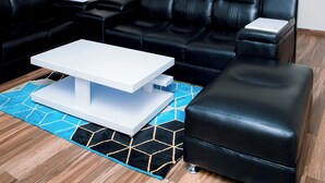 A modern living room with a sectional sofa, a white coffee table, and a blue patterned rug. - THE MOON APARTMENTS (Gisenyi)