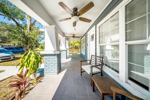 A covered porch with a ceiling fan, a bench, and a table.