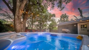 En bubbelpool med ett träd och ljusslingor i en trädgårdsmiljö.