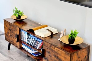 A wooden cabinet with a built-in bookshelf, a book, decorative items, and two small potted plants.