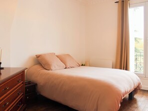 Een slaapkamer met een bed, een kaptafel en een raam met gordijnen.