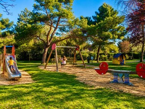 Un parque infantil con un tobogán, columpios y una casita de juegos.