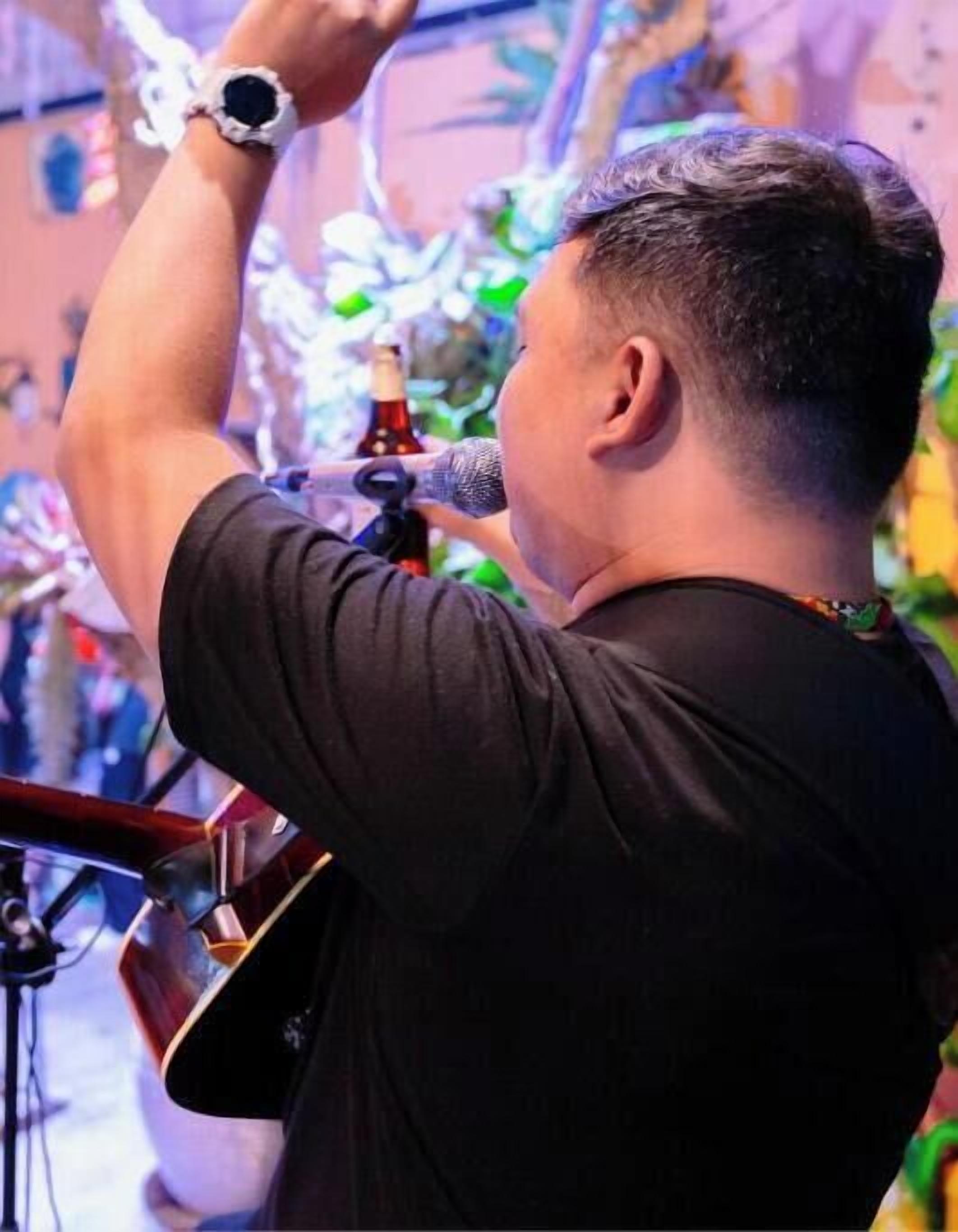 Uma pessoa tocando violão e cantando em um microfone.