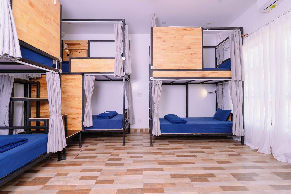 A dormitory room with bunk beds, wooden walls, and a checkered floor.