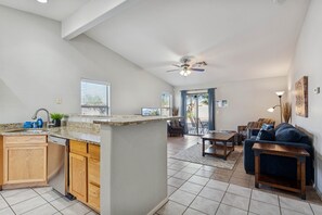 Uma sala ampla com cozinha, espaço para refeições e área de estar com sofá e cadeiras.