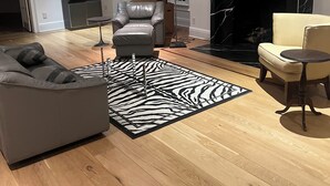 En moderne stue med pejs, læderlænestol, sofa og en måtte med zebra-mønster.