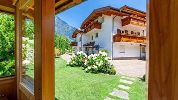 Ein Zimmer mit Holzrahmen und Blick auf ein weißes Gebäude mit Balkonen und einem Garten mit weißen Blumen.