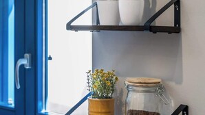 A wall-mounted shelf with two levels; the top shelf holds three potted plants, and the bottom shelf has a small yellow pot with flowers and a glass jar with a lid. - Palazzo Ducoss - Apt 7 - Two Bedroom One Bathroom (Valletta)
