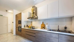 A modern kitchen with a built-in oven, microwave, and stainless steel sink. - Palazzo Ducoss - Apt 7 - Two Bedroom One Bathroom (Valletta)