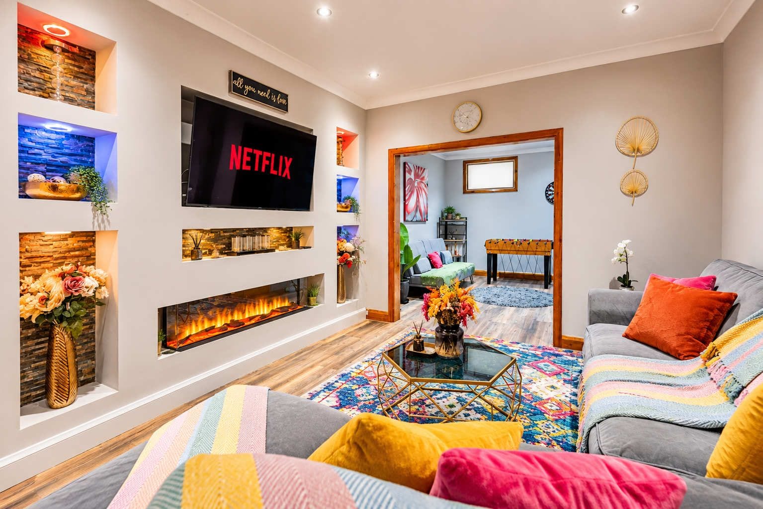Een moderne woonkamer met een open haard, een flatscreen televisie en een gezellige zithoek.