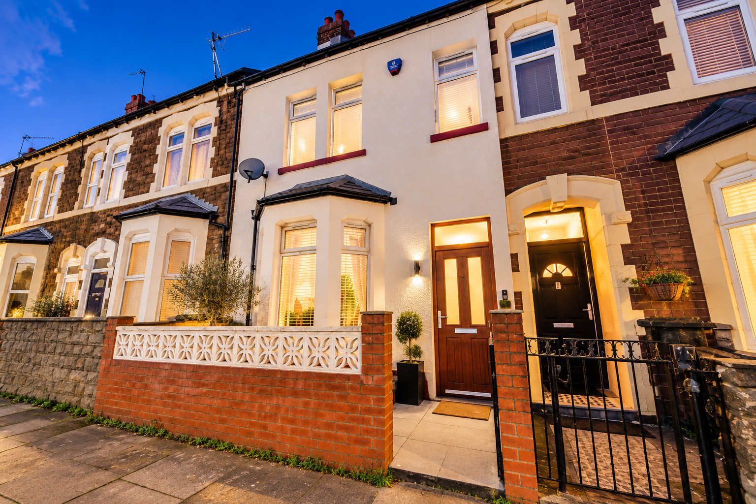 A row of terraced houses with a brick facade, white window frames, and a gated entrance.