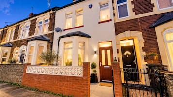A row of terraced houses with a brick facade, white window frames, and a gated entrance.