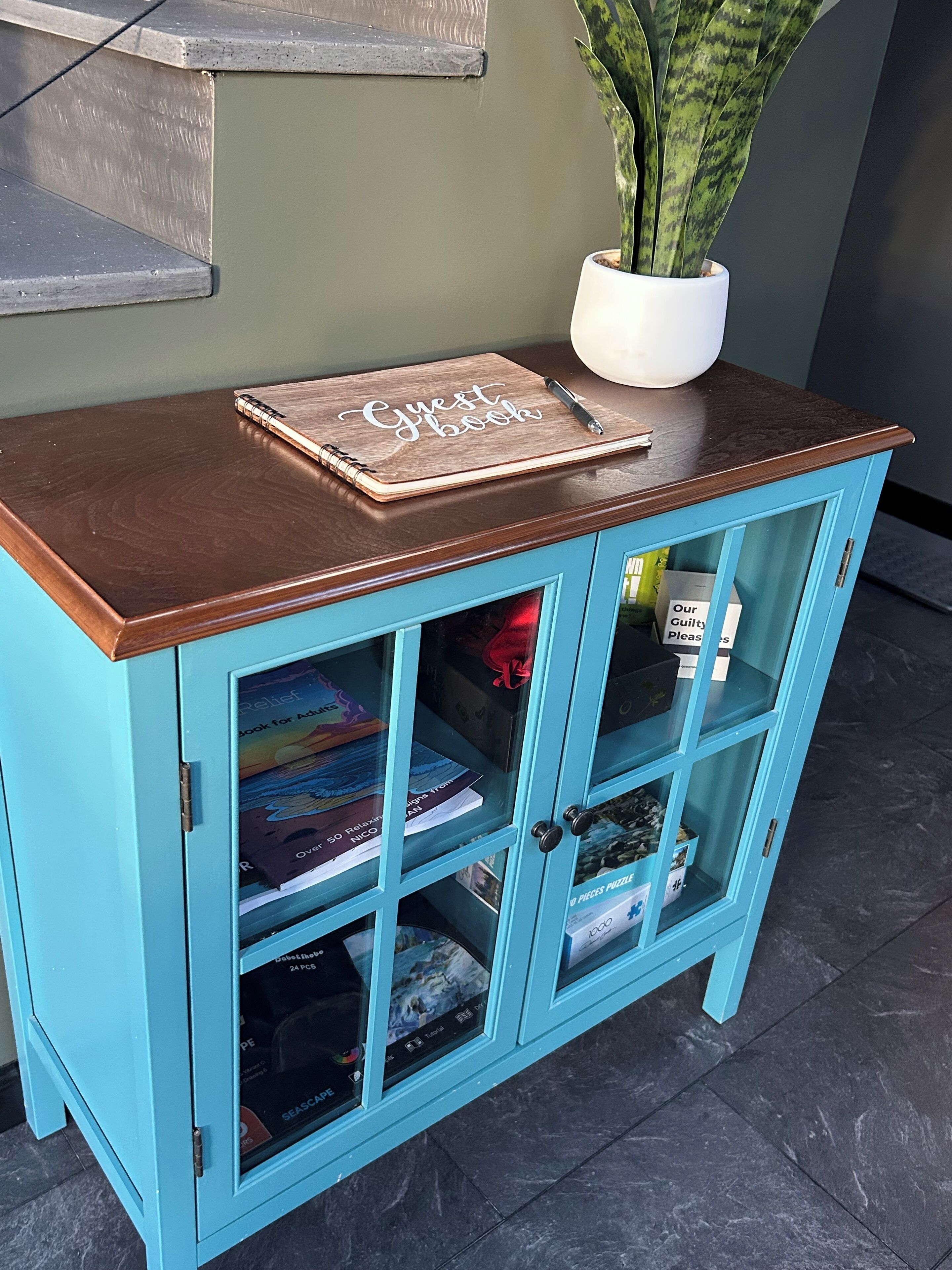 Un mueble verde azulado con tapa de madera, que contiene libros y un libro de visitas.