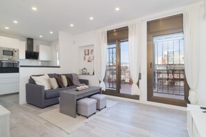 A modern apartment with a grey sofa, a small table, and a balcony with a view. - Guest Ready ‑ Bright & Stylish Flat w/ 3 Terraces (Barcelona)