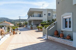 Ein modernes, zweistöckiges Gebäude mit überdachter Terrasse, Pflanzgefäßen und Blick auf die umliegende Landschaft.