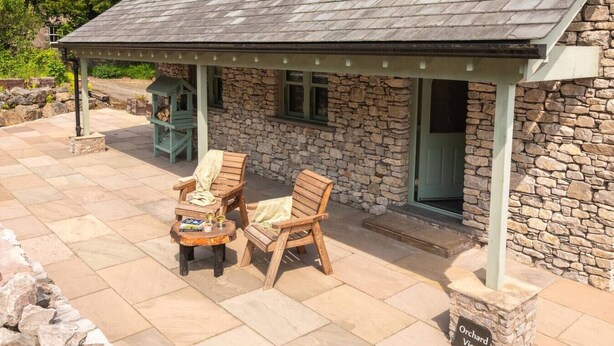 A stone building with a covered patio area featuring two wooden chairs and a small table with drinks. - Ellenboro House, Cosy Sleeps 2, Near Cartmel (Newton-in-Cartmel)