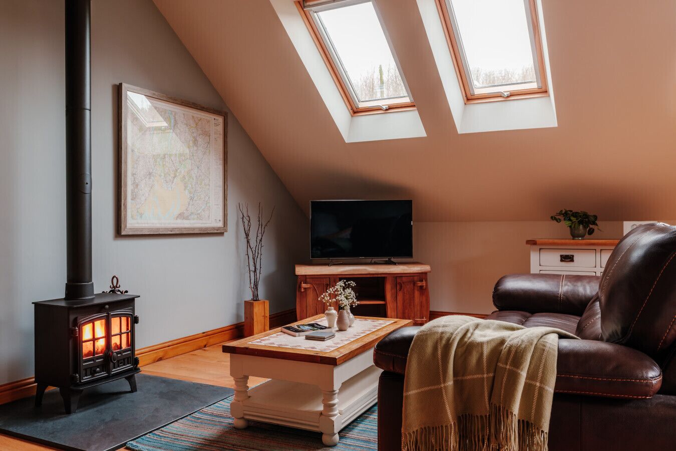 Una sala de estar acogedora con chimenea, televisor y sofá de cuero.
