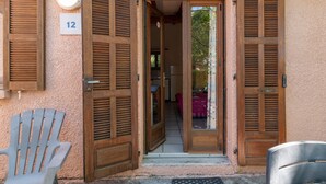 A building entrance with wooden shutters, a number '12' sign, and a chair outside. - Apartment 'Rico Plage 4 Personnes' with Private Terrace, Wi-Fi and Air Conditioning (Talasani)