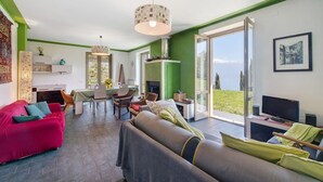 A modern living room with a sofa, a dining area, and a television. - Villa 'Agriturismo Casa Del Castagneto' with Lake View, Private Terrace & Wi-Fi (Gargnano)