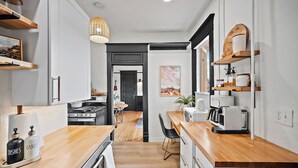 Een moderne keuken met houten aanrecht, een koffieapparaat en een eethoek met een stoel en tafel.