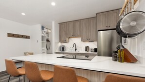 Uma cozinha moderna com uma ilha grande, banquetas e um exaustor embutido.