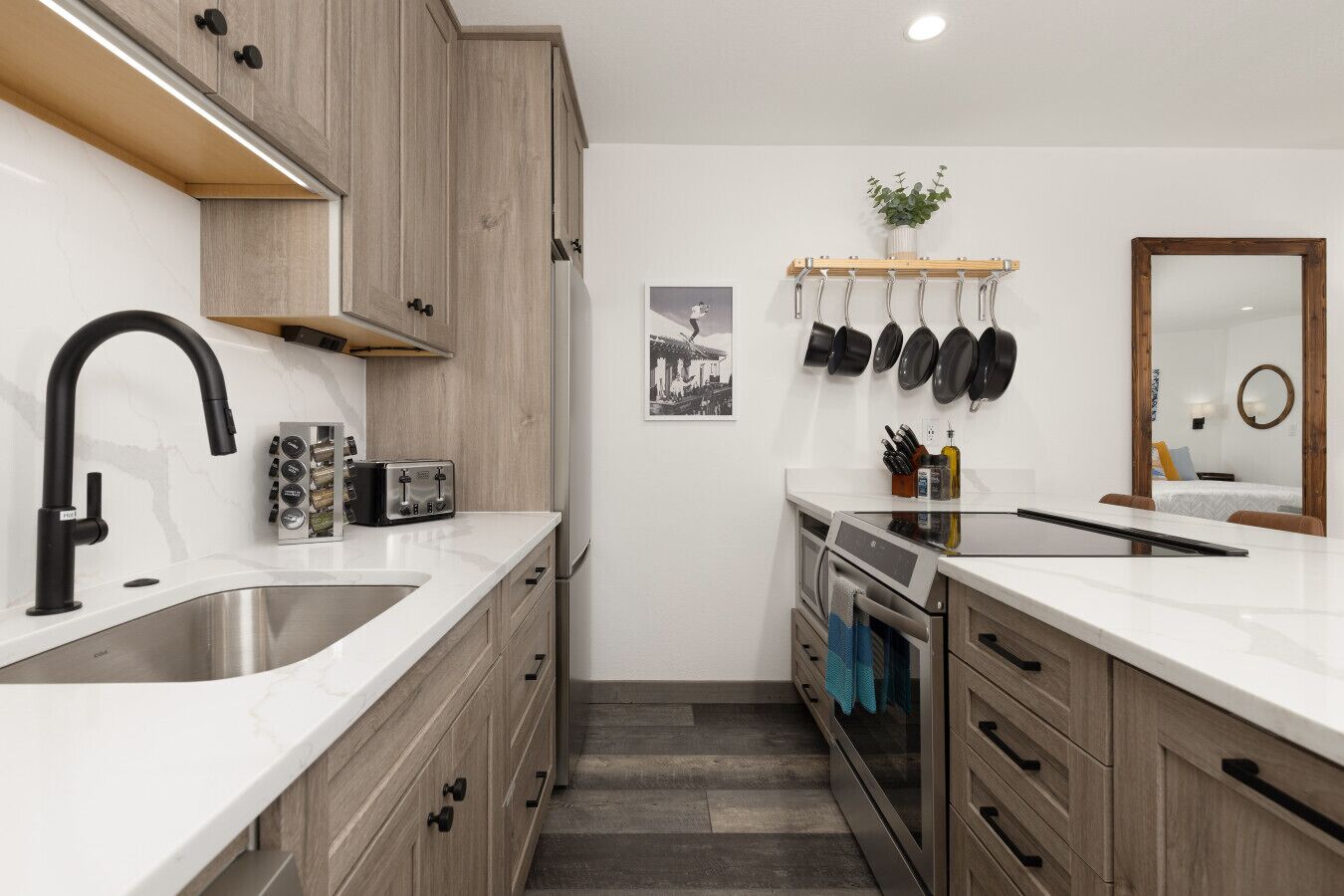 A compact kitchen with a sink, modern appliances, and a wooden cabinet.