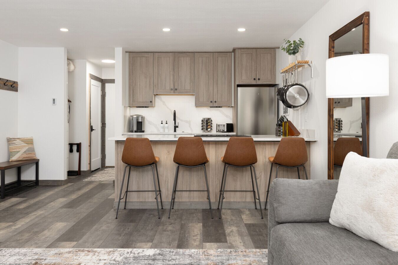 Eine moderne Küche mit Holzausstattung, einem Edelstahlkühlschrank und einer Bar mit vier Hockern.
