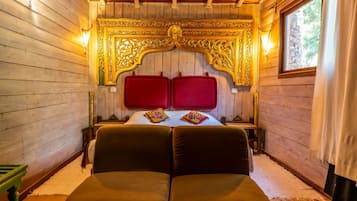 Camera da letto in una baita di legno, con un letto grande, due testiere rosse e una testiera decorata con intagli.
