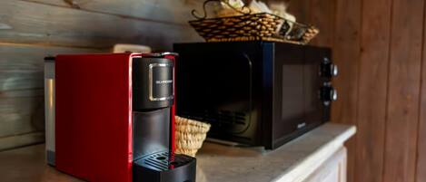 A red coffee maker and a black microwave on a wooden countertop.