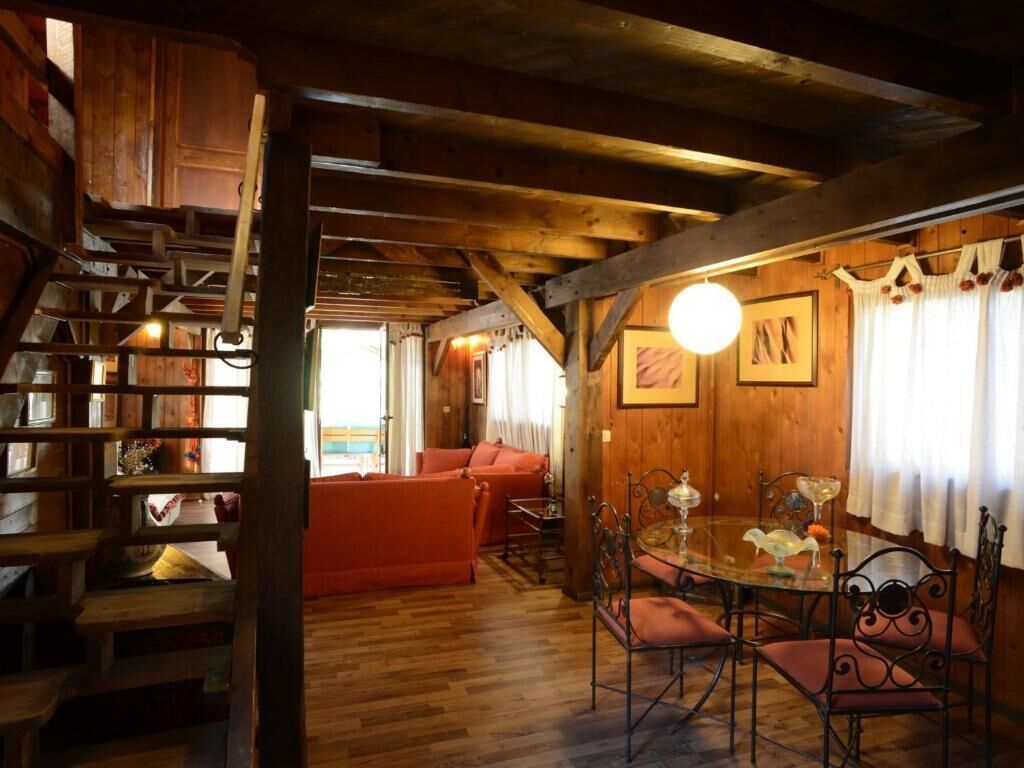 Un intérieur rustique en bois, avec un coin repas, un canapé rouge et un escalier.