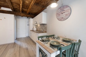 Una cocina con armarios blancos, techo de madera y un reloj de pared.