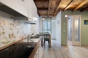 A kitchen with a wooden ceiling, a dining area with a table and chairs, and a door leading to another room.