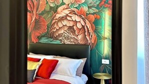A bedroom with a bed, pillows, a nightstand, and a wall mural. - Vacanze Romane Suite 7 Languages (Rome)