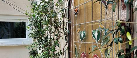 A window with a decorative stained glass design, a white window frame, and a wall with a textured surface.