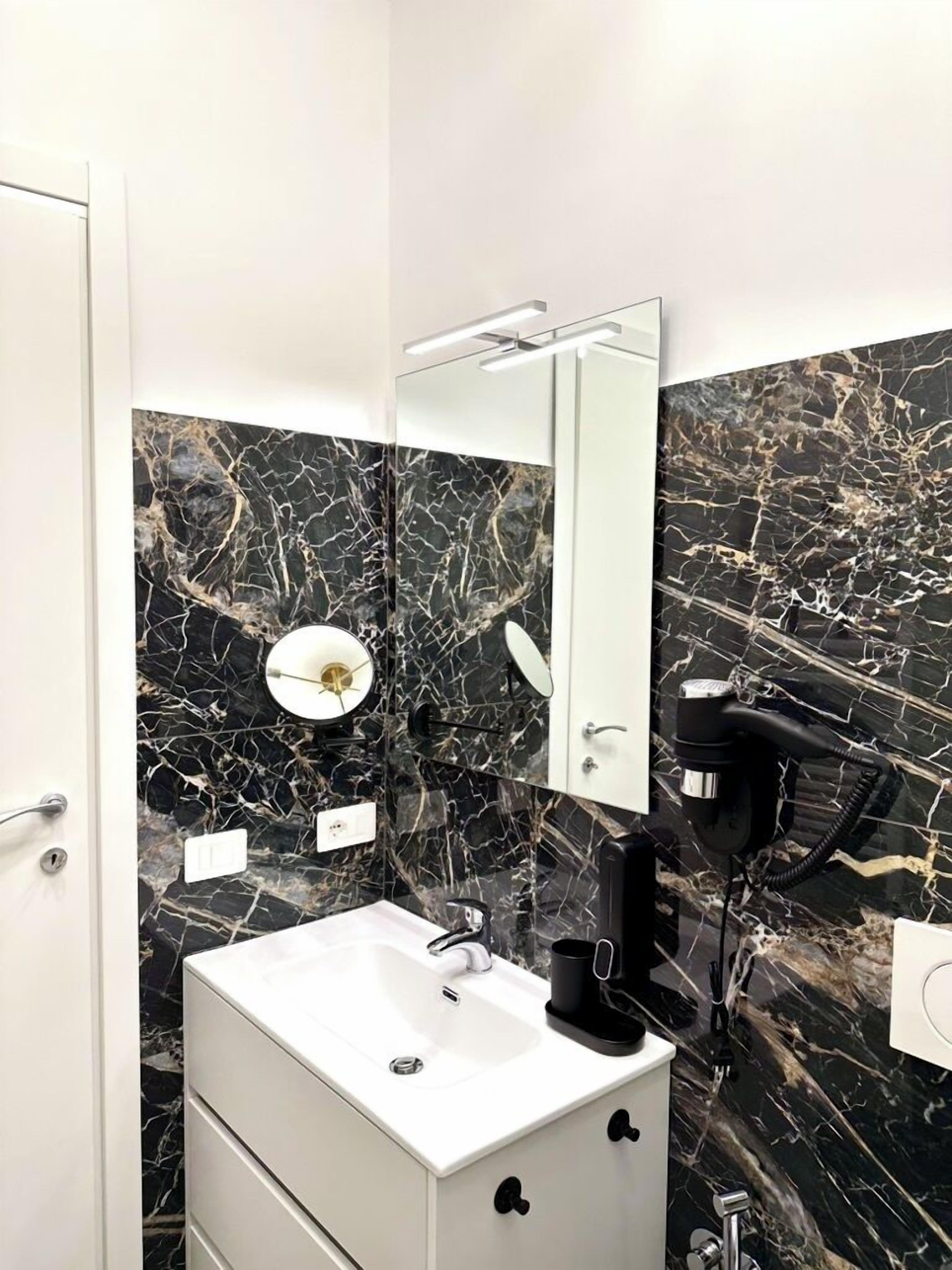A modern bathroom with a white sink, a mirror, and a hairdryer.