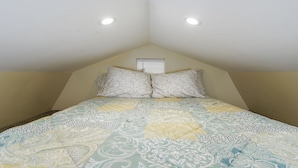 A bedroom with a bed, two pillows, a window, and a ceiling light.