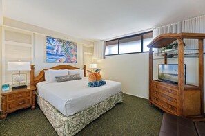 A hotel room with a large bed, a wooden nightstand with a lamp, a dresser with a mirror, and a painting on the wall. - Ocean View One Bedroom Kaanapali Shores 826 (Lahaina)